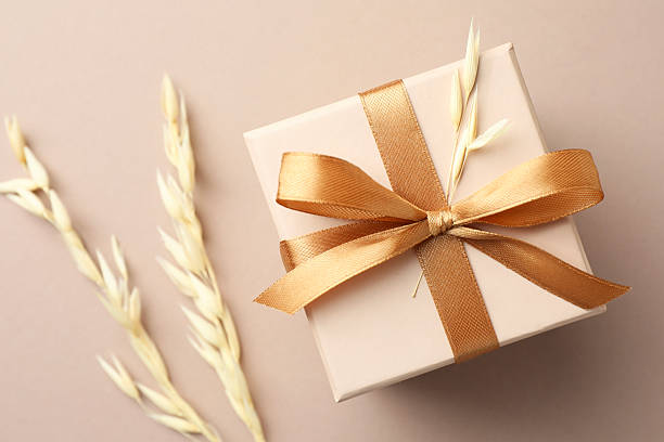 istock Gift box with golden bow and spikes on beige background, flat lay 2224512623