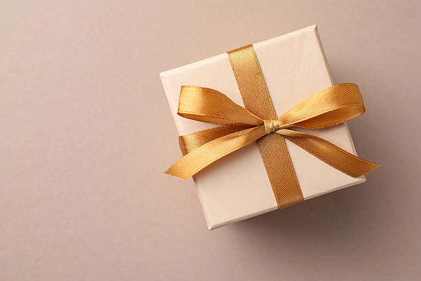 istock Gift box with golden bow on beige background, top view. Space for text 2224512670
