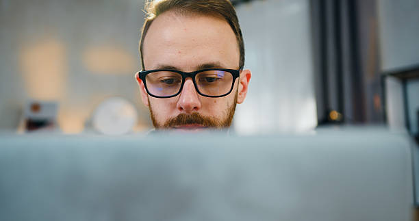 istock Handsome confident young bearded married man taking off his glasses and closing laptop when finished work on it ,work at home concept,close up 2224517143