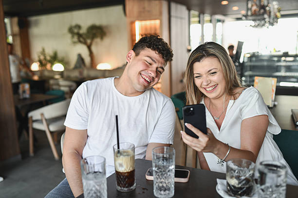 istock Cheerful Sister Sharing Funny Meme With Younger Brother, Causing Laughter 2224518022