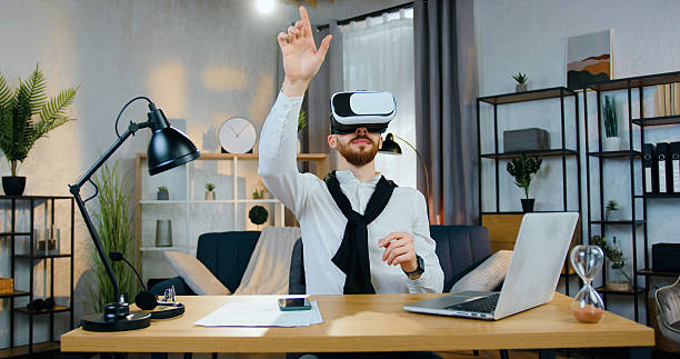 istock Likable positive confident bearded man in virtual reality headset sitting at the table in home office and working on imaginary screen,close up 2224518091