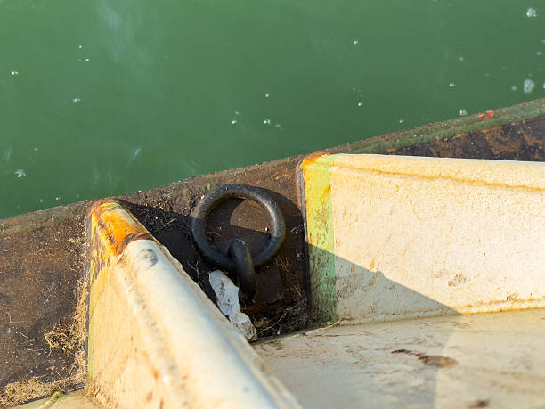 Rusty boat corner with metal ring near green water, lifestyle