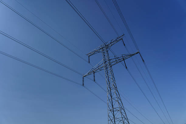 A high-voltage transmission tower with power lines stretching across a clear blue sky, symbolizing energy infrastructure and modern technology