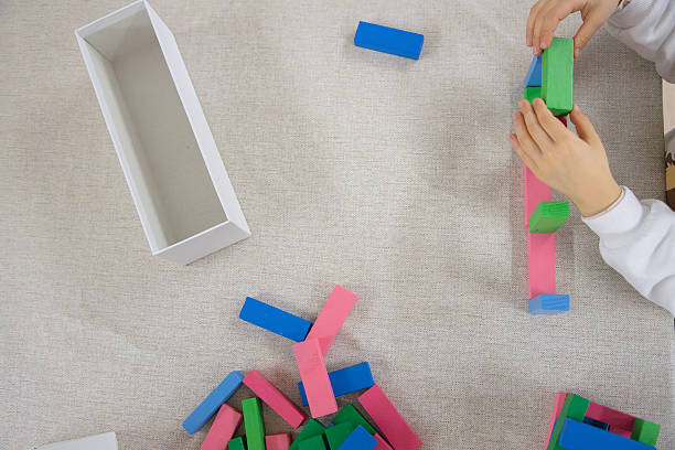 istock A young child plays indoors during the day, focusing intently while building a structure with colorful wooden blocks, developing fine motor skills, creativity, and early cognitive abilities. 2224521914