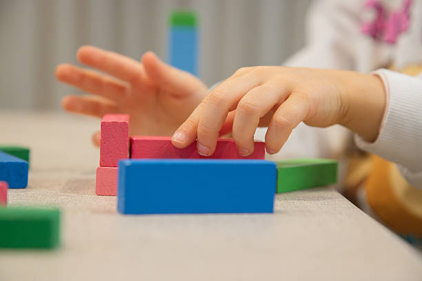 istock A young child plays indoors during the day, focusing intently while building a structure with colorful wooden blocks, developing fine motor skills, creativity, and early cognitive abilities. 2224521929