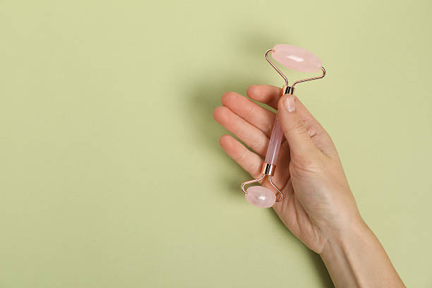 istock Woman with face roller on light green background, top view. Space for text 2224522143