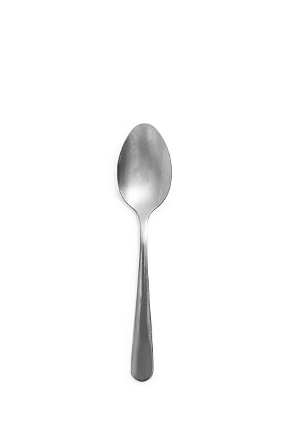 Close-up view of a stainless steel spoon placed on a smooth reflective surface, with soft warm lighting highlighting its curved metal shape and polished texture.