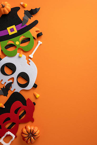 istock Festive Halloween vertical masks with pumpkins and candy placed on a bright orange surface 2224532045