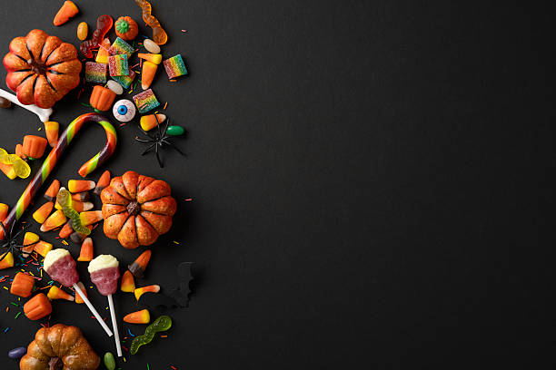 istock Colorful Halloween candy and pumpkin decorations arranged festively on a black surface 2224532049