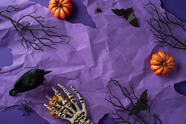 istock A spooky Halloween composition featuring decorations such as pumpkins, skeleton hand, a crow, branch and bats against a crumpled purple background, creating an eerie atmosphere 2224532054