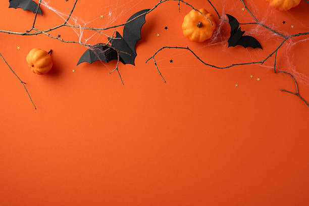 istock Decorative arrangement featuring pumpkins and bats on orange background symbolizing Halloween festivities 2224532055