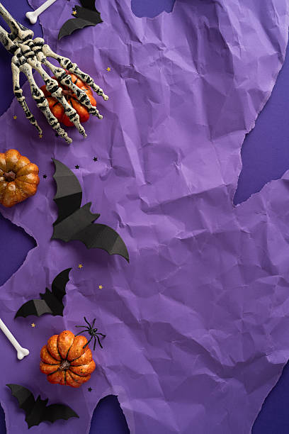 Decorative Halloween vertical theme with bats, pumpkins, a skeleton hand, and a purple surface. Perfect for spooky, festive, or party-related designs and themes