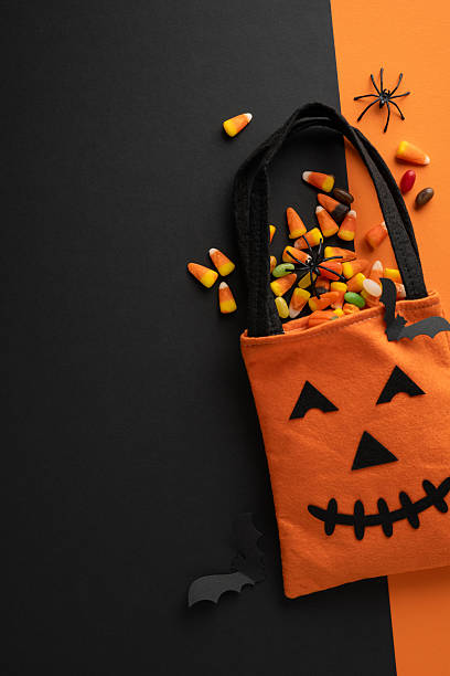 istock Orange jack-o'-lantern vertical bag filled with various candies, placed on a dark Halloween theme 2224532096