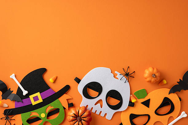 istock Colorful Halloween masks with pumpkin, witch, and skull designs on bright orange backdrop, surrounded by small pumpkins, bats, candy corn, and spider decorations 2224532125