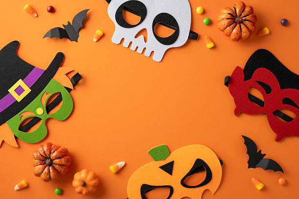 istock Festive masks alongside pumpkins, candy, and bats arranged artistically on a vibrant surface 2224532129