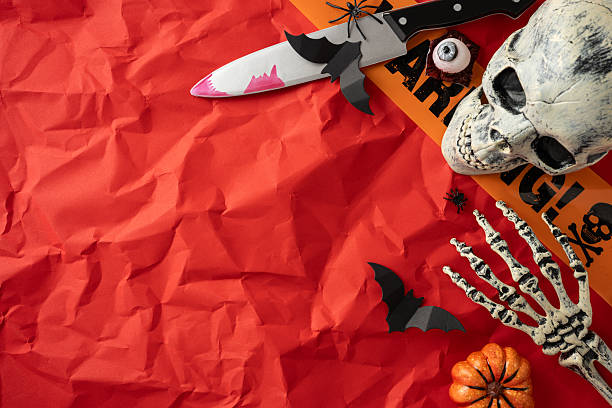 istock Halloween decorations displayed creatively on crinkled red paper, featuring pumpkins, a skull, and eerie props 2224532133