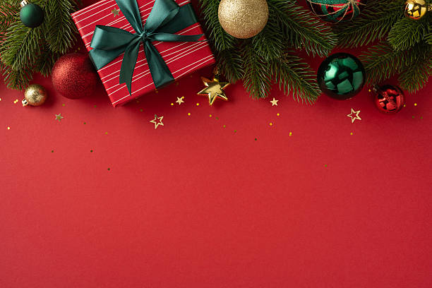 istock Christmas composition featuring ornaments, wrapped gifts, and festive tree branches against a red backdrop 2224532144