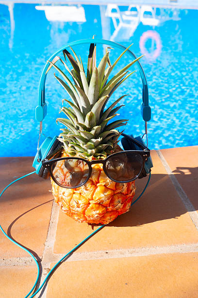 pinapple near swimming pool in sunglasses and headphones