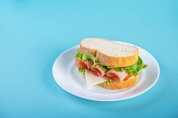 istock Sandwich with ham, cheese and lettuce on a blue background 2224532680