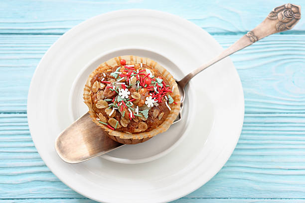 cinnamon banana bread oat muffin topped with christmas sprinkles on a cake shovel on a plate on wood table, close-up, not AI generated