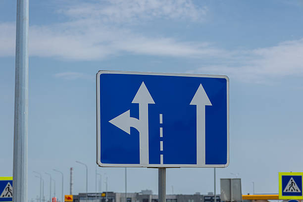 istock A road sign displays arrows pointing straight and left, guiding drivers at an intersection under a blue sky 2224534140