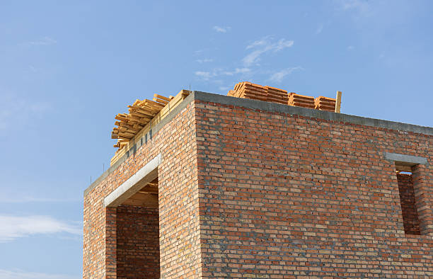 A frame-centered protruding corner of a brick building facade against a clear blue sky.