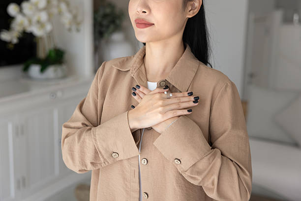 Woman praying touches her chest with both palms pressed together