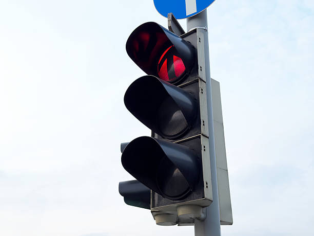 istock Red traffic light against blue sky in urban setting 2224543448