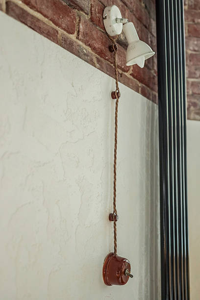 istock Vintage-style wall lamp with ceramic switch and textile cord on a textured wall and exposed red brick background, combining retro and industrial interior design 2224543902