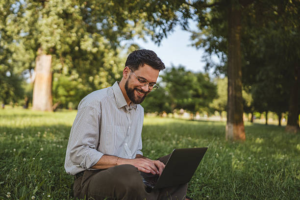 istock businessman sit on grass in nature and use laptop for work or leisure 2224546209