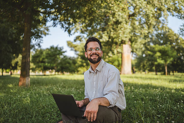 istock businessman sit on grass in nature and use laptop for work or leisure 2224546233