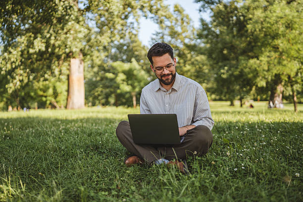 istock businessman sit on grass in nature and use laptop for work or leisure 2224546245