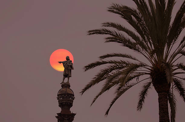 Barcelona, Spain - July 16, 2024: Columbus monument featuring a statue pointing towards the sea isolated on a clean blue background with copy space.