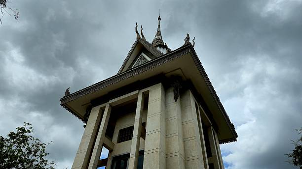 Phnom Penh, Cambodia - 25 June 2025. The Choeung Ek Memorial Stupa stands under dark clouds, containing victims' skulls from the Khmer Rouge era and serving as a solemn genocide remembrance site.