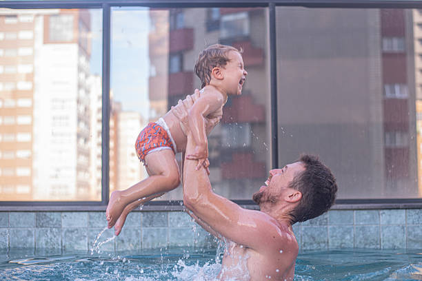 istock Dad throwing his child up in the pool 2224555156
