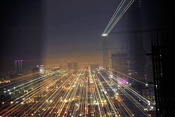 Tower cranes glowing brightly at night, constructing a new structure against a backdrop of a dark, starry sky filled with city lights