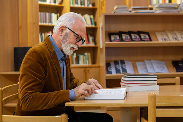 istock Senior man reading books in the public library 2224558825