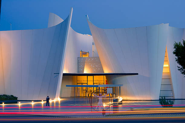 Puebla, Pue., Mexico - March 27, 2021: shot in the evening with rays from passing cars on the walls of the entrance to the Museo Internacional del Barroco. The walls are illuminated with yellow lamps. The sky is dark - the road is concrete, the walls are made of tiles.