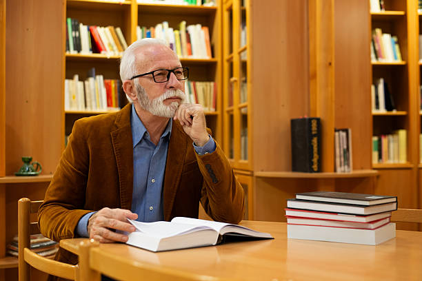 istock Senior man reading books in the public library 2224559784