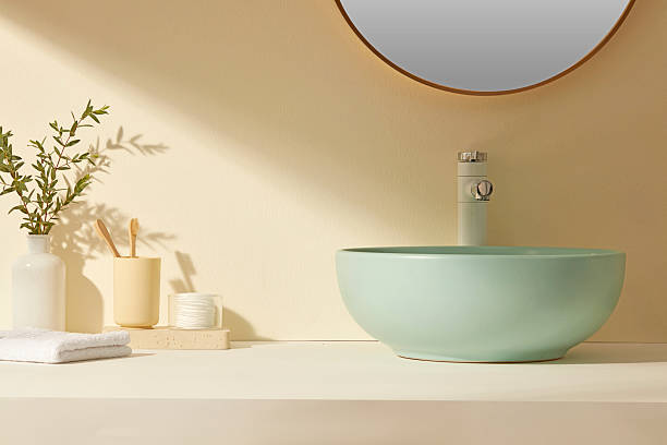 istock Warm-toned modern bathroom with soft green sink and sunlight streak across surface. Central empty area allows clean product placement. 2224567302