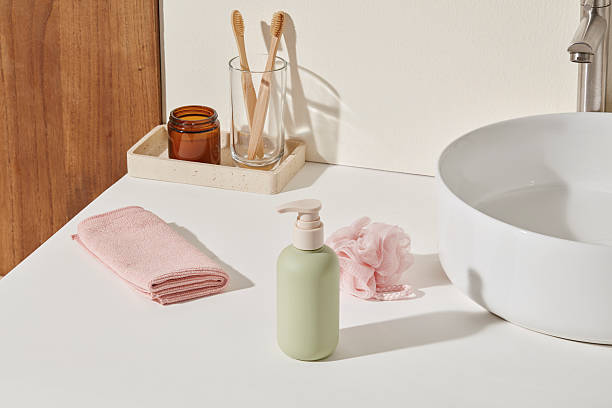 istock White sink counter with bamboo toothbrushes, green bottle and blush towel. Empty right-side surface with soft shadowsperfect for layout design or product highlight zone. 2224567348