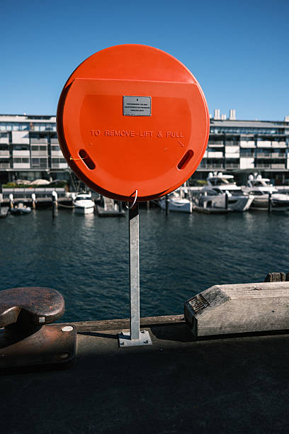 Lifebuoy in an orange colored case on the side of a pier.