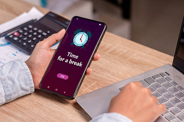 istock Take a break from your activity or phone concept. Person holding smartphone with time for a break notification. 2224569904