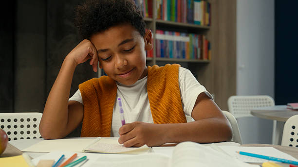 istock School classroom studying African American kid little boy son schoolboy pupil learner student tired sleepy child yawning learn lesson boring homework write test exam at desk study primary education 2224576033