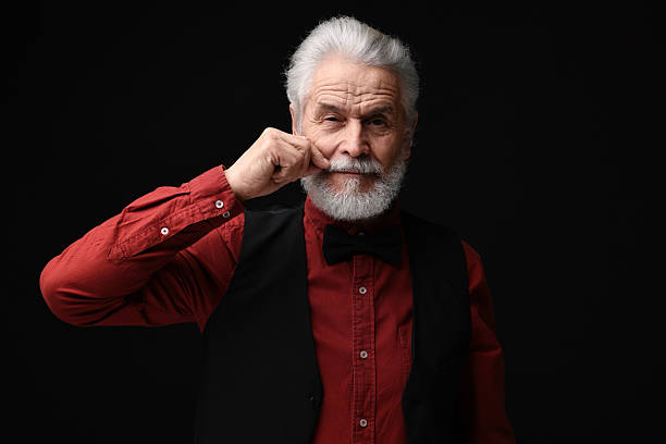 istock Senior man touching mustache on black background 2224578352