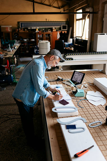 istock Mature artisan taking notes and designing a sign in his workshop 2224581487