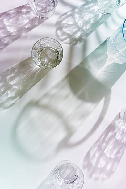istock Water Glasses and water jug with palm leaf Shadows and sunlight Reflection on white background, colored minimal aesthetic top view summer still life, refraction throug crystal cups, caustics 2224581585