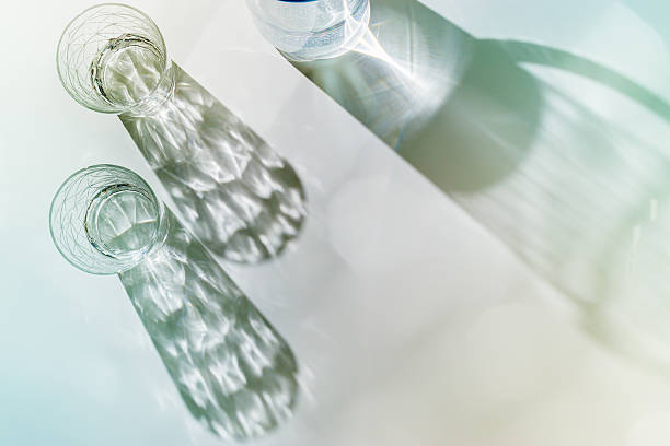 istock Water Glasses and water jug with Shadows and sunlight Reflection on white background, colored photo minimal style, aesthetic summer still life, refraction throug crystal shine cups, caustics 2224581594