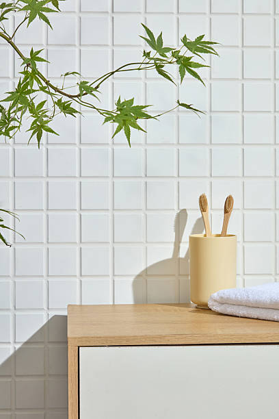 istock Bamboo toothbrushes in a ceramic cup and folded towel sit neatly on a wood counter. White tile wall and soft natural light create an open Japanese-style space ideal for product overlay. 2224582953