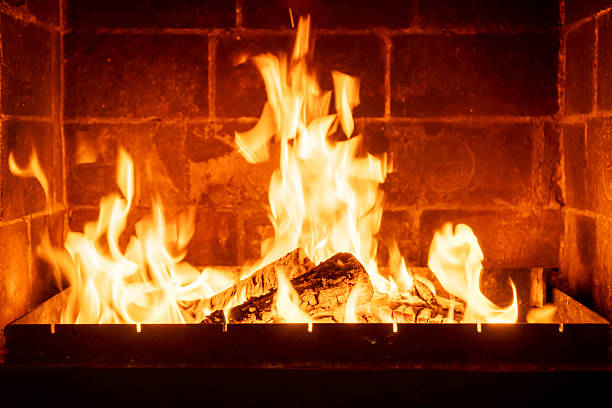 Burning fireplace logs with high flames inside brick hearth, cozy interior warmth, traditional home heating, rustic ambiance, romantic cabin atmosphere, winter season comfort, firewood crackling sound